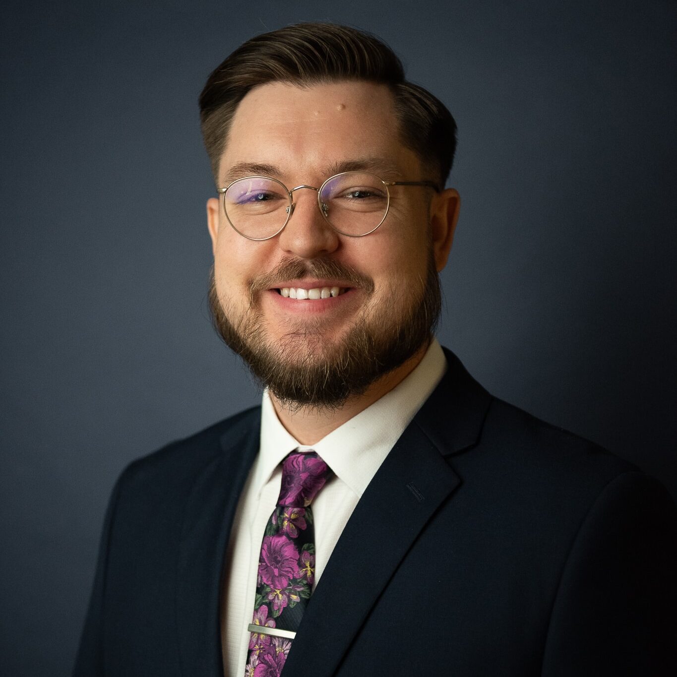 a man wearing a suit and tie smiling and looking at the camera